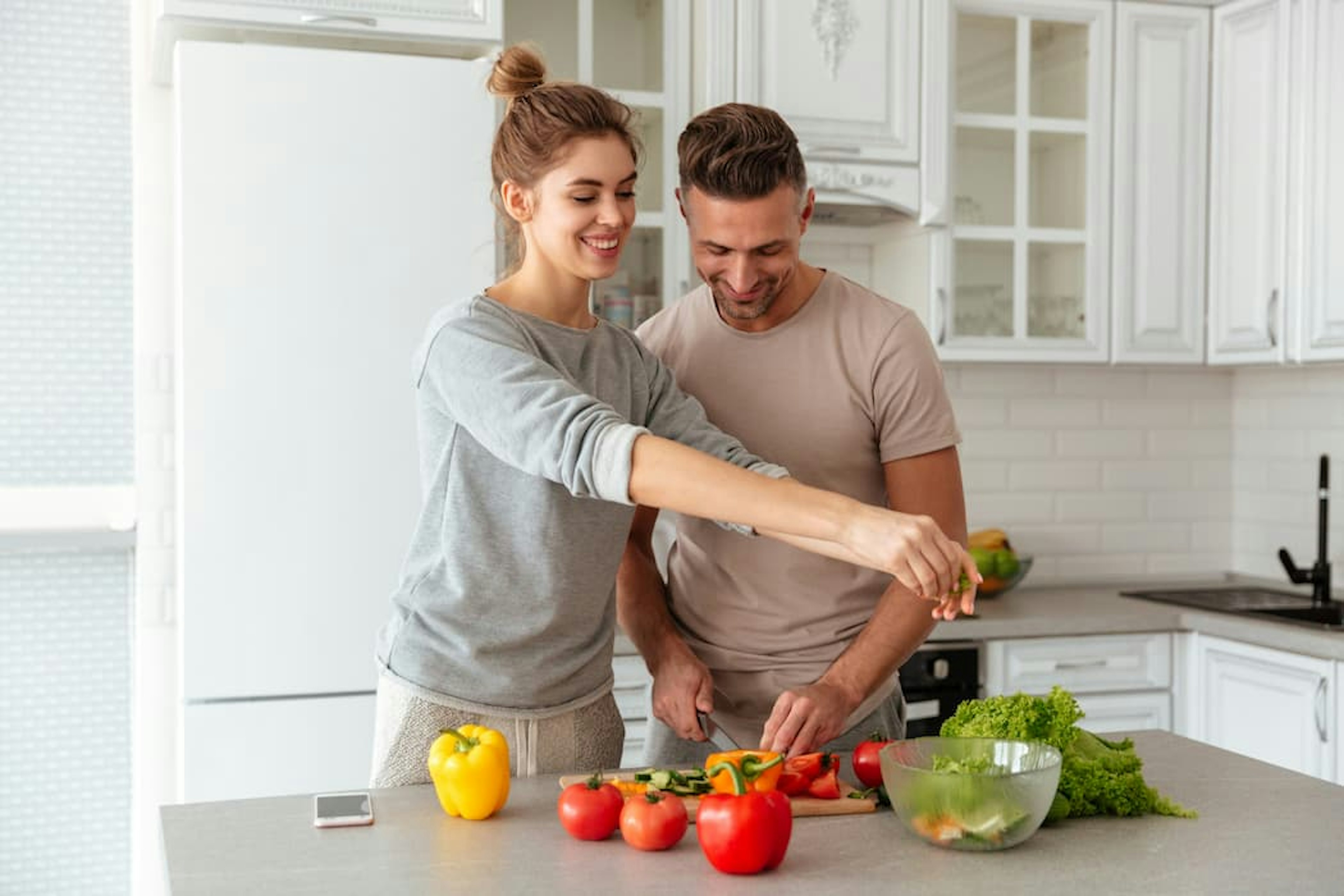 ES Um homem e uma mulher preparando uma salada em uma cozinha.
